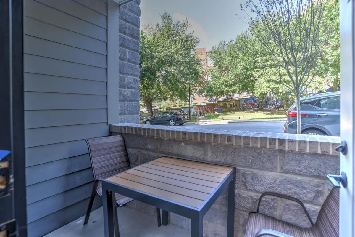 An exterior shot capturing a private patio or terrace area with a table and chairs, overlooking the lively city street. The scene is bright and relaxed, blending indoor comfort with outside energy, and hinting at the proximity to Asheville’s vibrant urban life.